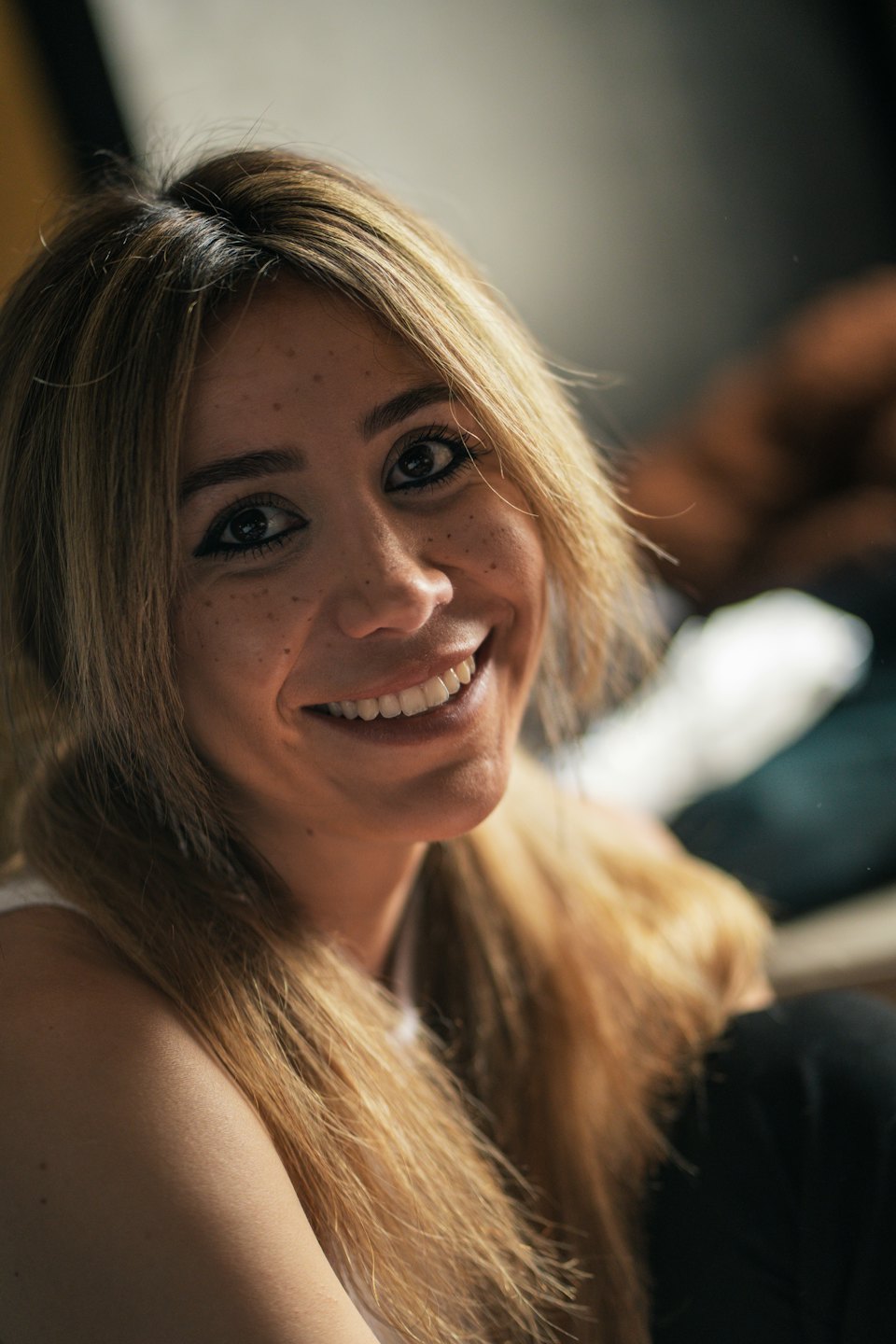 Donna bionda con lentiggini che sorride in un ambiente interno.