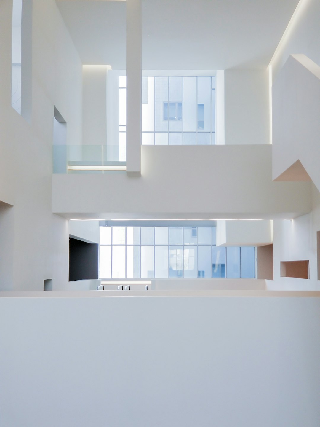 Interno moderno bianco con forme geometriche e grandi finestre.