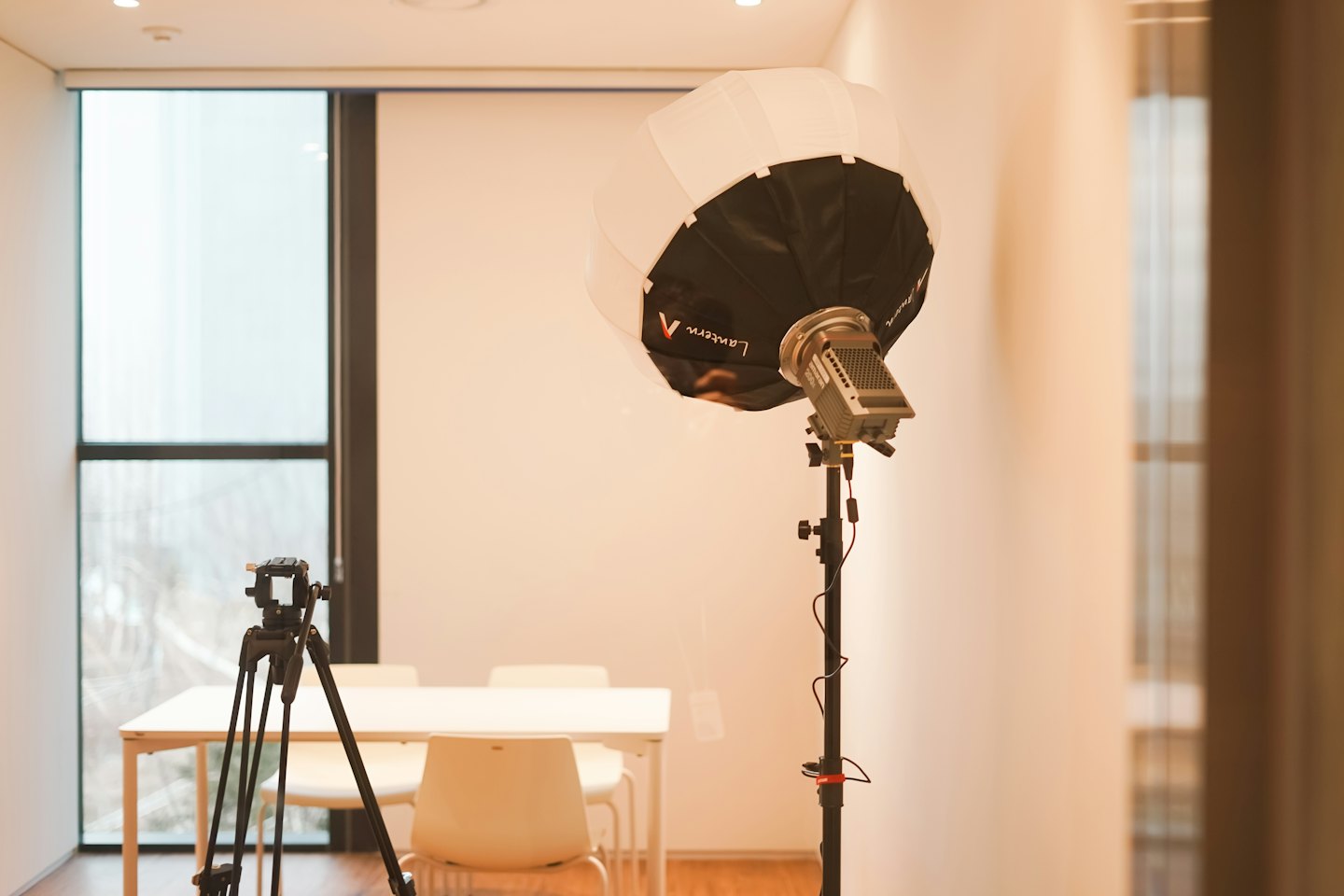 Studio fotografico con treppiede per fotocamera e luce softbox.